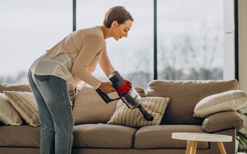 Young woman with rechargeable vacuum cleaner cleaning at home